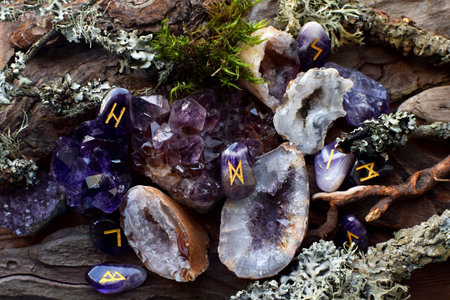 Precious amethyst crystals on wooden background with Scandinavian runes made of amethyst stones....