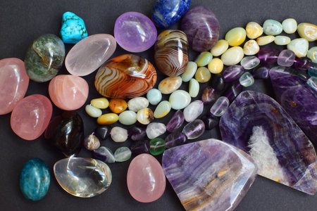 Background of beautiful natural colored semi-precious stones and beads of fluorite and amazonite. Purple amethyst, agate, labradorite, jasper, kyanite, lapis lazuli on a dark background close-up.の写真素材