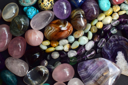 Background of beautiful natural colored semi-precious stones and beads of fluorite and amazonite. Purple amethyst, agate, labradorite, jasper, kyanite, lapis lazuli on a dark background close-up.の写真素材