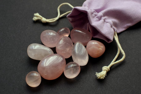 Beautiful natural semi-precious stones of rose quartz in a cloth bag on a black background.の写真素材