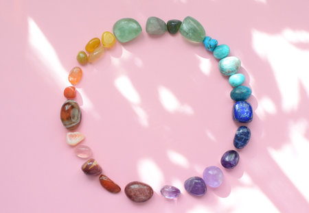 Precious stones for zodiac signs on a pink background in the sunbeams. The circle is laid out with natural minerals. Predictions, witchcraft, spiritual esoteric practice.の写真素材