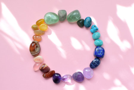 Precious stones for zodiac signs on a pink background in the sunbeams. The circle is laid out with natural minerals. Predictions, witchcraft, spiritual esoteric practice.の写真素材