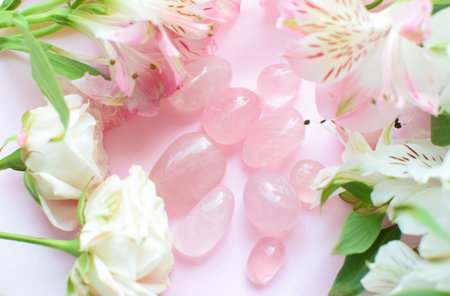 Rose quartz crystals and a bouquet of roses and alstroemerias. Healing crystals, the magic of gemstones.の写真素材