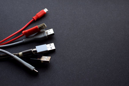 Multiple USB peripheral cables (Universal Serial Bus). USB data and power cables on a dark background. USB cable, charger. Copy space.の写真素材
