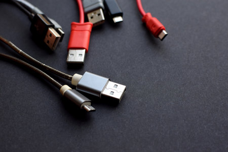 Multiple USB peripheral cables (Universal Serial Bus). USB data and power cables on a dark...