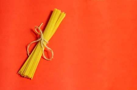 sheaf raw spaghetti on a red background isolatedの写真素材