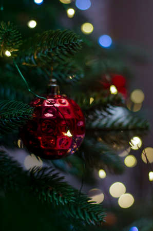 Bokeh red ornament Christmas decoration toy hanging on a spruce branch with bokeh blured lights on background.の写真素材