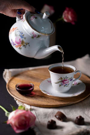 pouring hot steaming tea from a vintage teapot into glass cupsの写真素材