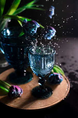 out of focus Ice cubes splashing into glass of waterの写真素材