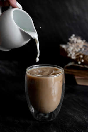 Pouring milk into the coffeeの写真素材