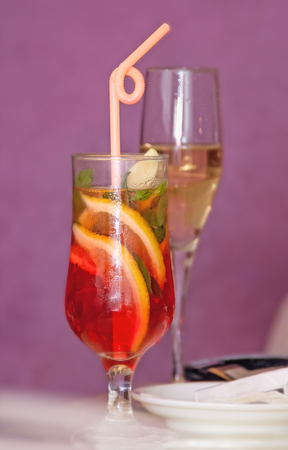 single glass transparent wine glass with a cocktail, slices of lemon and a straw, the second with champagne on a pink backgroundの写真素材