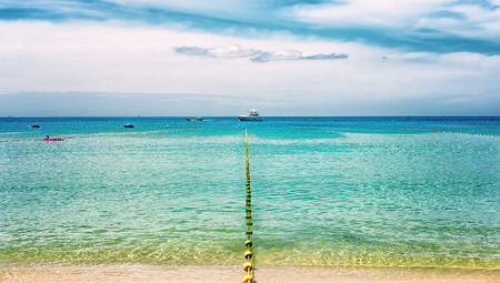 seascape on a Sunny day with the fence disappearing into the distance and sea vessels on the horizonの写真素材