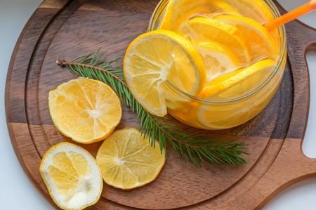 orange cool drink of lemonade with slices of orange and Mandarin in a transparent bowl with ice and a straw for cocktailの写真素材