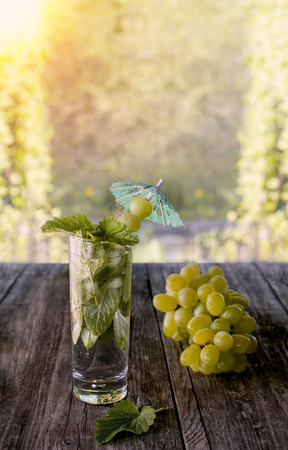 Detox water mint, grape juice and ice in a glass on a green background bokeh and grapes on a Sunny day.の写真素材