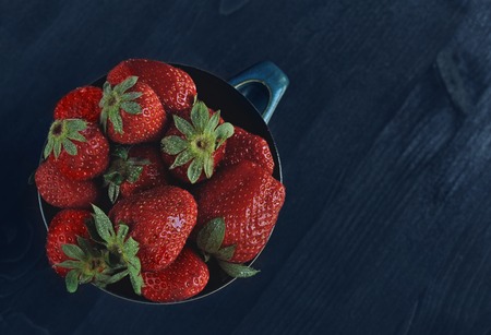Ripe strawberries in a bowl on a dark background in rustic style.の写真素材