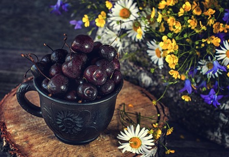 Ripe juicy cherries in a clay pot with flowers in a rustic style.の写真素材