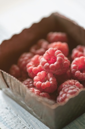 Raspberries close-up in a brown box on a light background. The horizontal frame.の写真素材