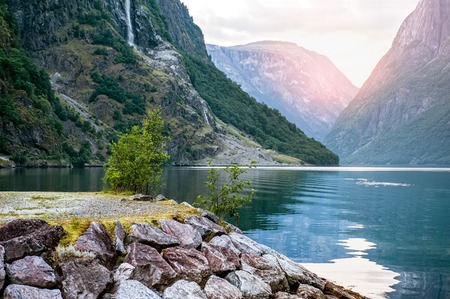 Golden sunrise in the mountains, Gudvangen Norway with reflection in the water of the fjord. The horizontal frame.の写真素材