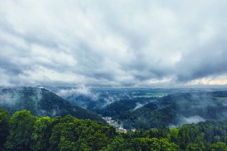 Beautiful view on a small town in the mountains with a dramatic cloudy sky. The horizontal frame.