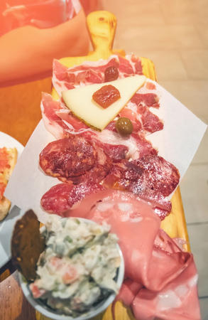 Plate in a cafe with different types of sliced deli meat and cheese with sauce. The vertical frame.の写真素材