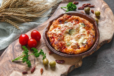 Round sausage pizza Margherita on a beautiful natural blackboard of olive . Selective focus. The horizontal frame.の写真素材