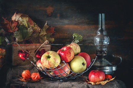 Autumn still life of apples in a basket with a lamp and candles. The horizontal frame.の写真素材