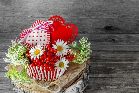 Two hearts in a wicker basket with berries and flowers on Valentine's Day in a rustic style. The...