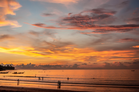 Beautiful sunset on the coast with light with a luminous cloud. Silhouettes of people walking on the beach. The horizontal frame.の写真素材
