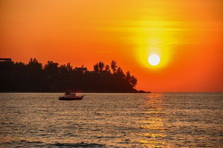 Beautiful sunset on a tropical beach. The ship sails in the last rays. The horizontal frame.の写真素材