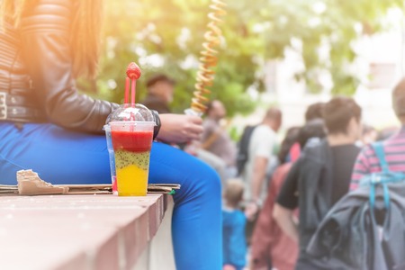 A glass of smoothie made from fresh fruit with strawberry stands on the parapet on the background of blurred street on a Sunny day. The horizontal frame.の写真素材