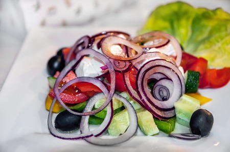 Low-calorie salad of mozzarella, vegetables, onions and olives on table in cafe. Low-calorie diet. Healthy food.の写真素材