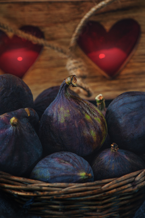 Ripe figs lies on the background of the candle holder in the shape of a heart. Selective focus. Low key. The vertical frame.の写真素材