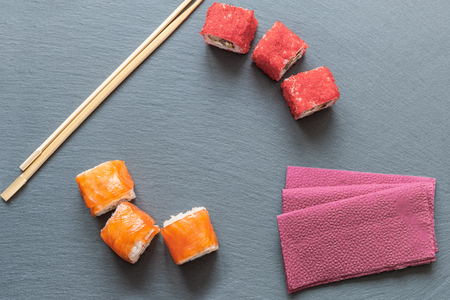 Japanese sushi made of rice and sea bass, shrimp and smoked eel with flying fish caviar with Philadelphia cheese, chopsticks on a black plate . Copy space. The view from the top.の写真素材