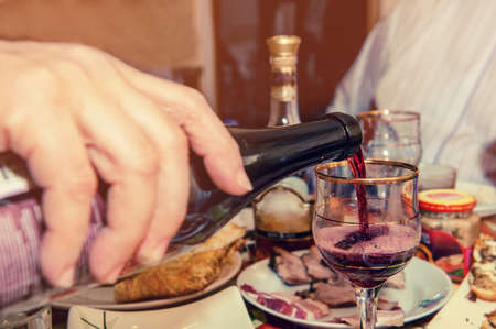 Red wine flows into the glass in the evening at dinner with friends.の写真素材
