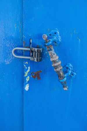 Damaged blue metal sheet with vintage wooden handle and new metal lock.の写真素材