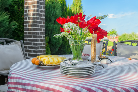 Beautiful bouquet of red tulips in a transparent vase on a table outdoorsの写真素材