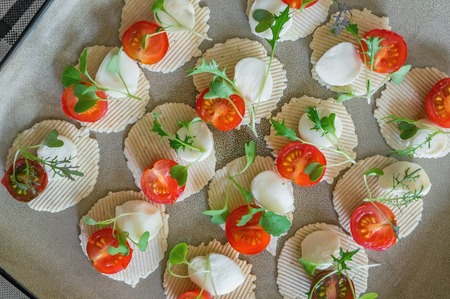 Mozzarella and tomatoes with thyme, arugula and Basil are on corn chips. Preparation of canapes....
