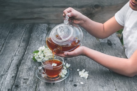 The girl pours hot tea in a transparent glass Cup.の写真素材