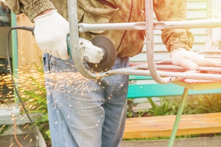 The metal pipe is cut out by a chain saw by the hand of the masterの写真素材