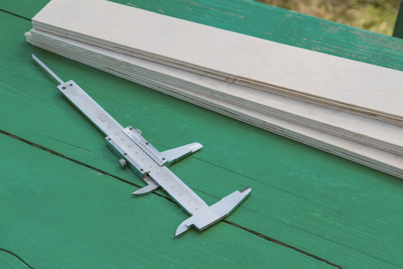 A tool to measure the width of a wooden panel on a Sunny day in the garden