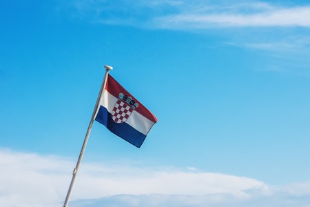 Croatian flag flying on wind, blue sky with clouds in background.の写真素材