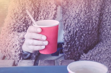 girl holding a red paper Cup of coffee.の写真素材