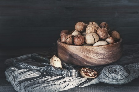 Pecan and macadamia nuts with a device for chopping nuts on a wooden background. Copy space.