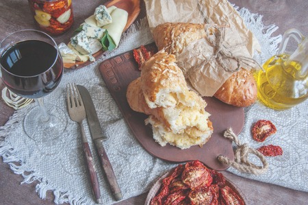 A glass of dry red wine and Italian Focaccia bread with cheese and olive oil and sun dried tomatoes. Selective focus.の写真素材