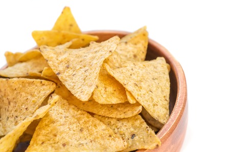 Corn tortillas or nachos, fried over an open fire, lie in a wooden bowl. Copy space.