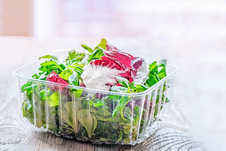 Mix from fresh organic salads in plastic transparent packaging on a wooden table. Copy space.の写真素材