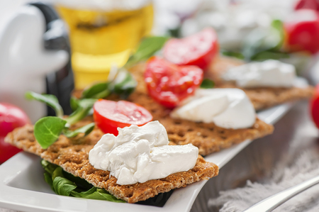 Burato cheese toasts with tomatoes and green salad on a white plate.の写真素材