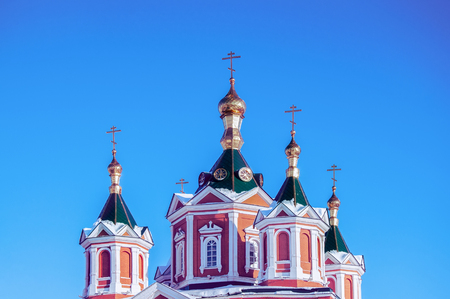 Golden domes with golden crosses over a monastery in Russia against a blue clear sky.の写真素材