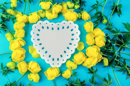 Beautiful blue background with a heart-shaped copy space from a white plate with yellow buttercup...