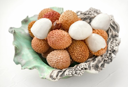 Fresh organic lychee fruit in beautiful crockery on a rustic woodenの写真素材